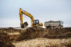 pelle mécanique sur une butte de terre qui excave des terre polluée dans un semi remorque