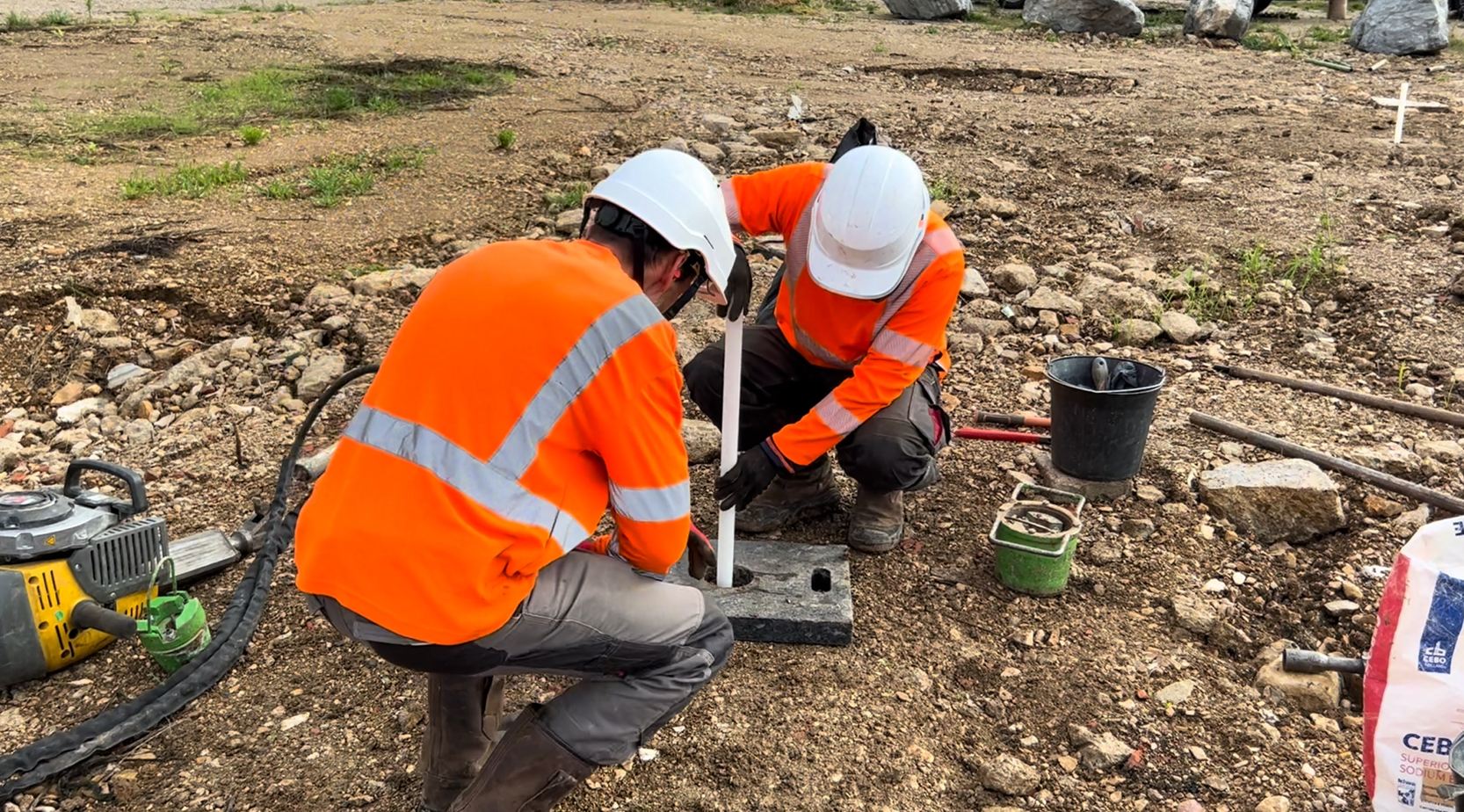 deux ingénieurs en tenu de chantier entrain de poser un piézair dans le sol